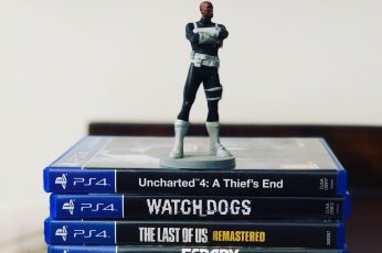Assorted-title Sony PS4 game cases with figurine on top