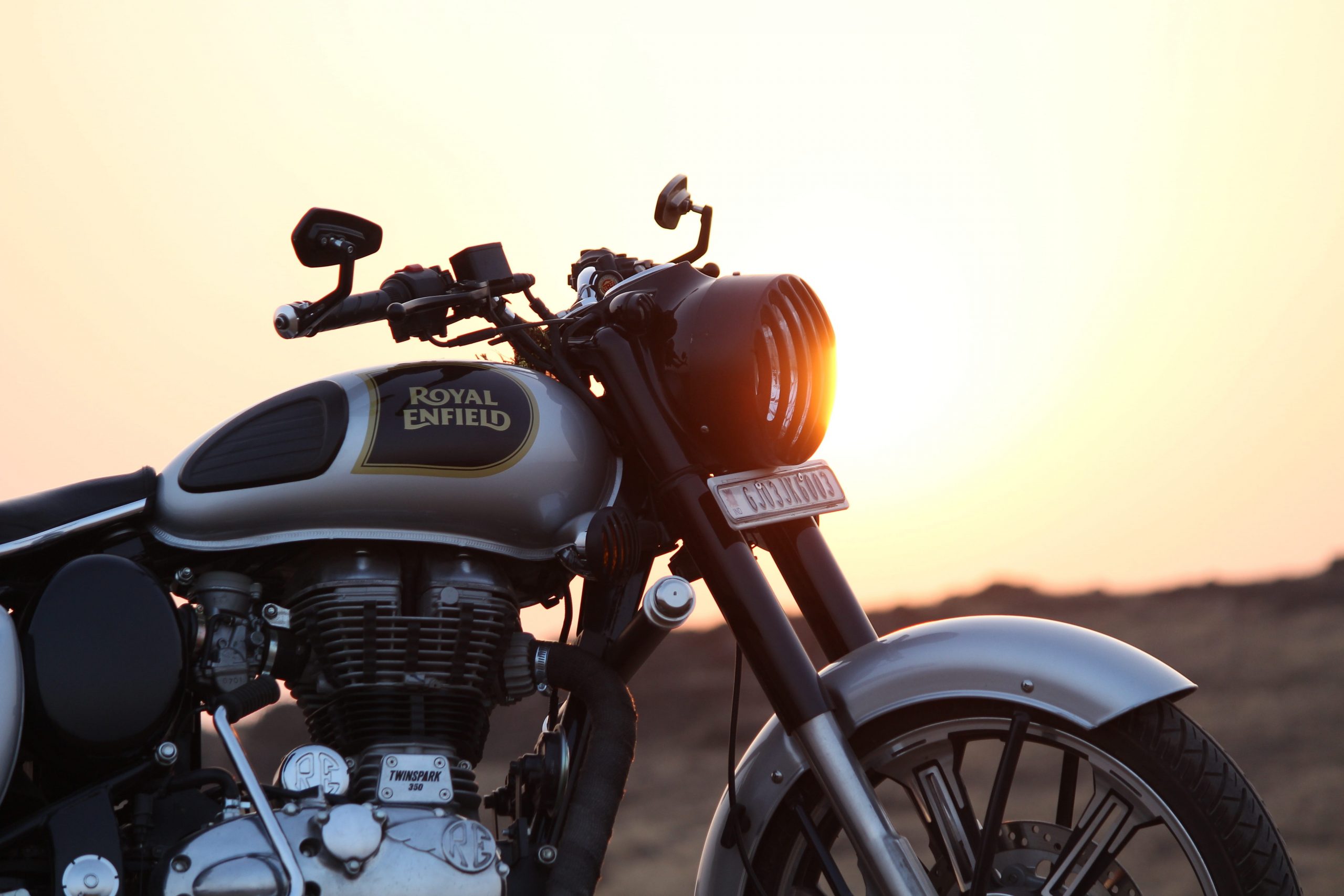 Black and grey Royal Enfield motorcycle on brown field, bullet wallpaper
