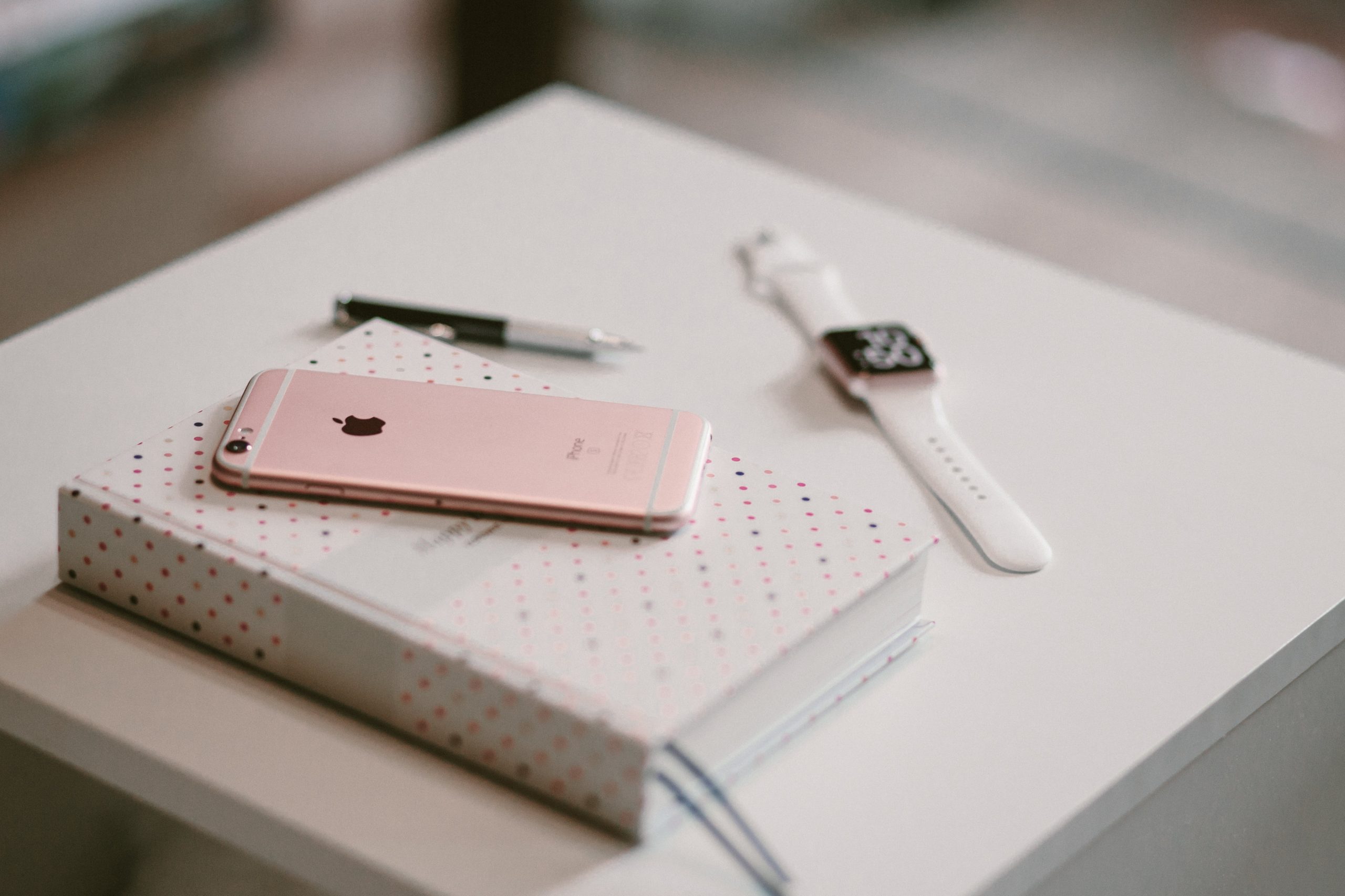 Wallpaper rose gold iPhone 6s on white book near gold aluminum case Apple Watch