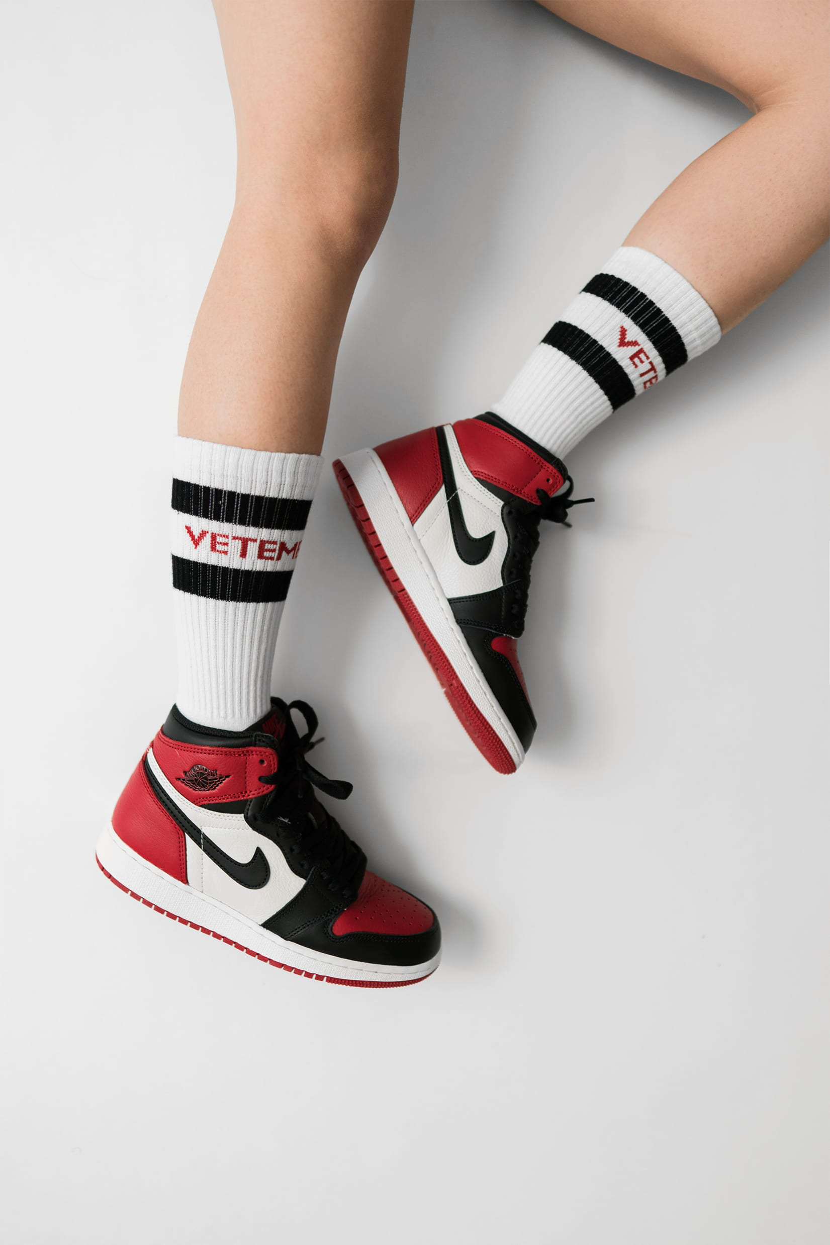 Wallpaper person wearing pair of black toe Air Jordan 1’s, white-red-and-black Nike Air Jordan 1’s