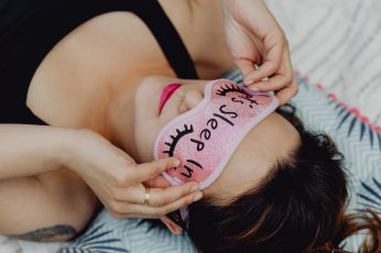 Joyful girl relaxing in bedroom – top view of brunette women in pink sleeping mask wallpaper