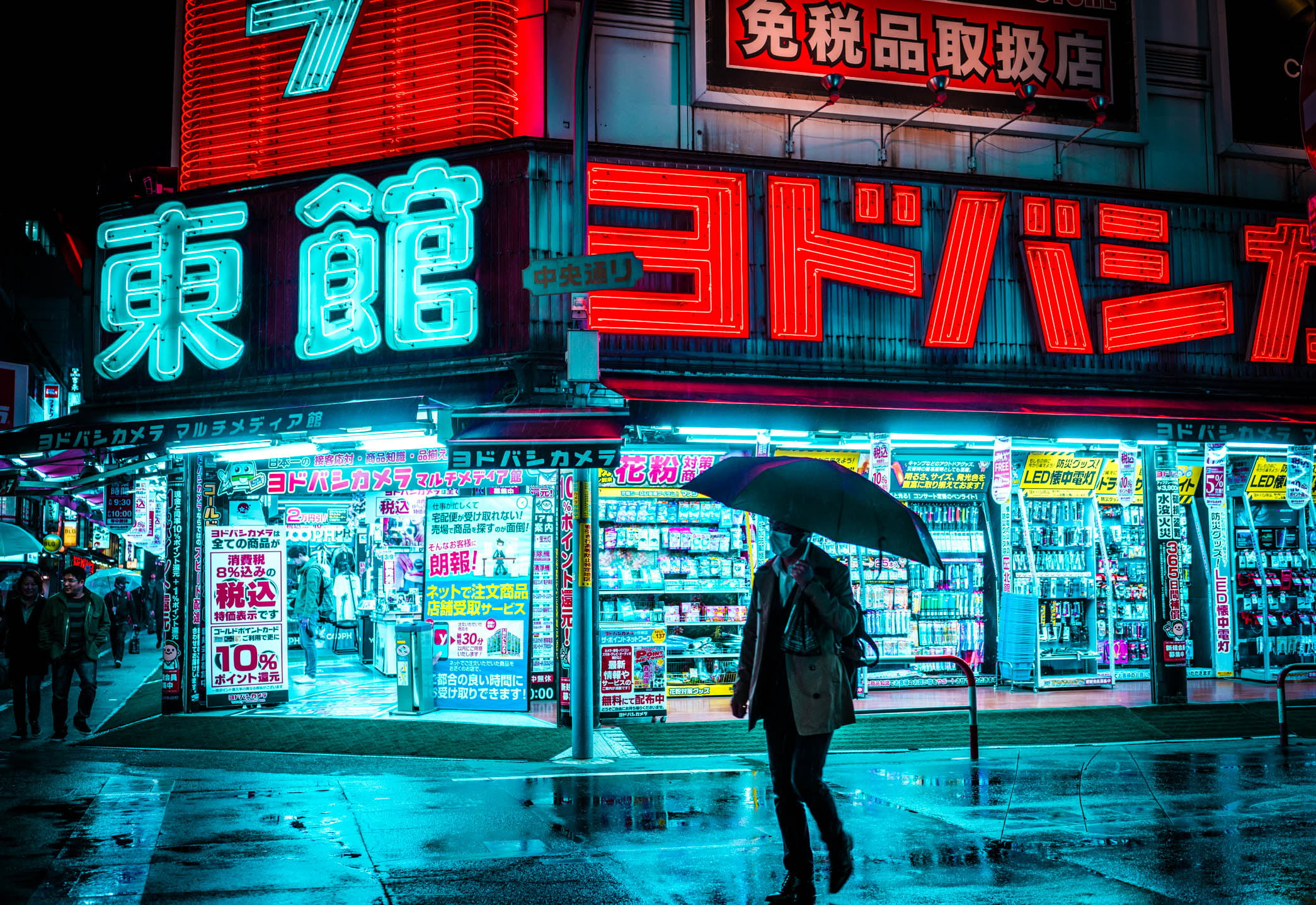 Man holding umbrella walking on the street near store during nighttime wallpaper