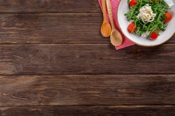 Salad on white ceramic plate on brown wooden table wallpaper, background