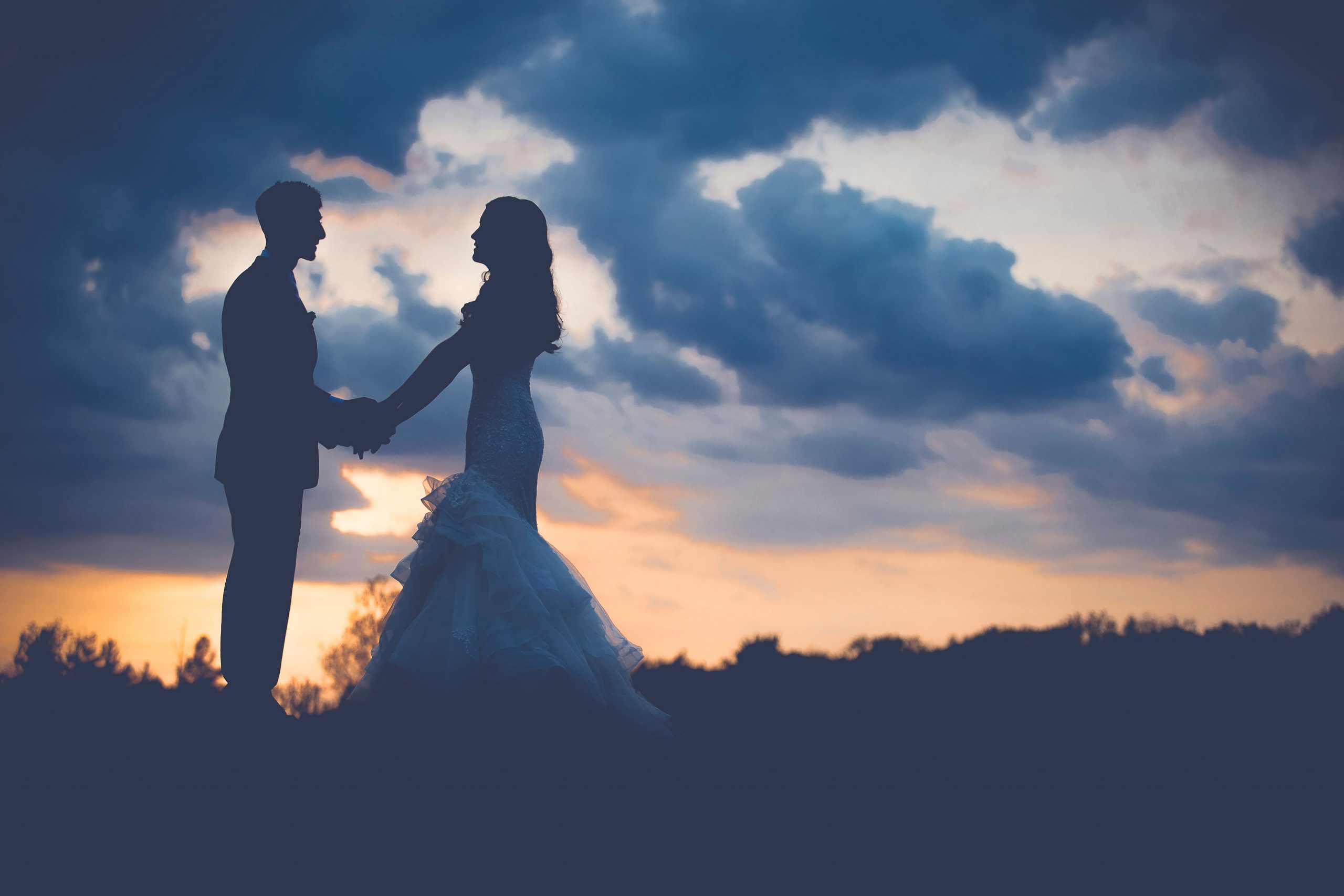 Silhouette of man and woman standing during sunset wallpaper