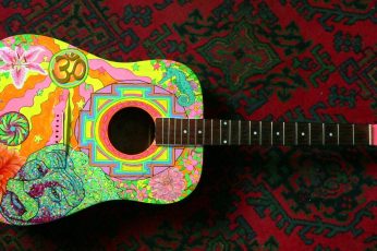 Black and multicolored dreadnought acoustic guitar on wallpaper
