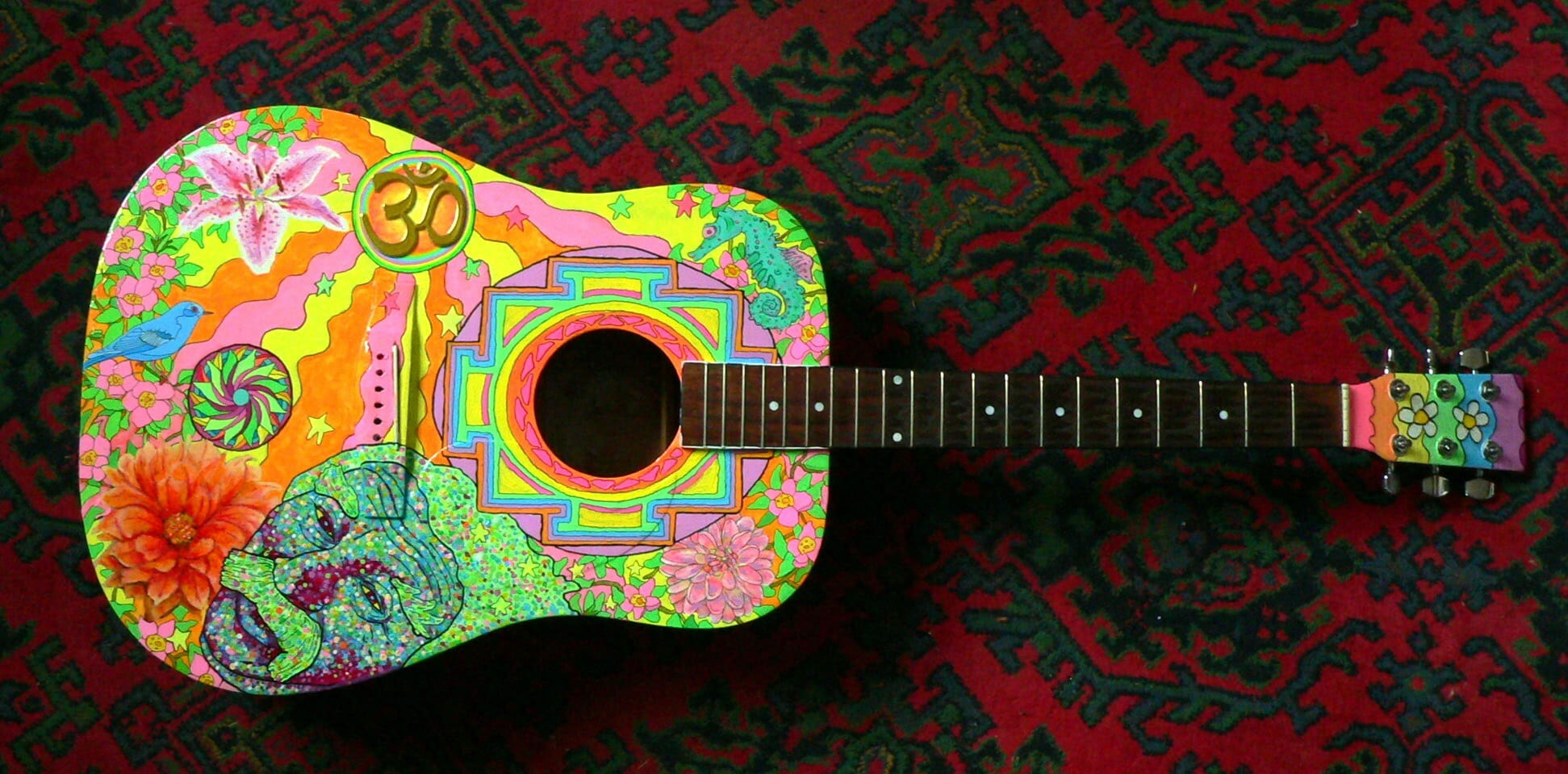 Black and multicolored dreadnought acoustic guitar on wallpaper
